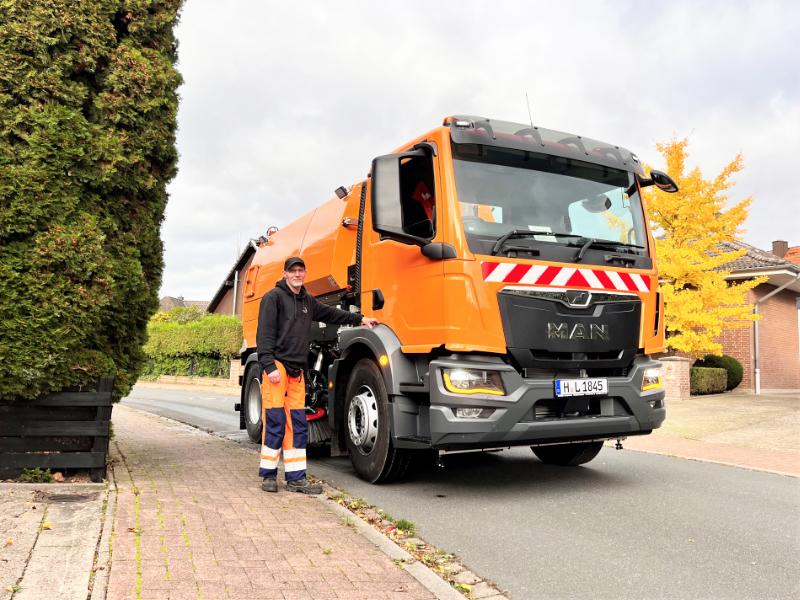 Mike Beyersdorf vom Betriebshof steht vor seiner neuen Orangenen Kehrmaschine 