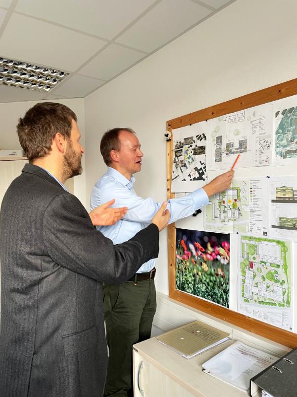 Marcus Tuerr und Hauke Schroeder am Arbeitsplatz stehend vor einer Tafel voll mit Plänen. Foto von Ilka Hanenkamp Ley